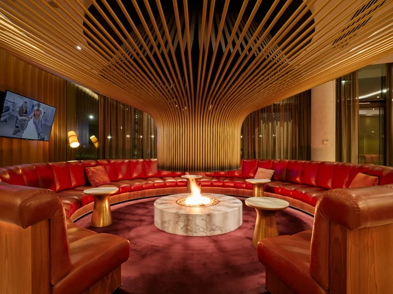 Circular lounge with a central fireplace and red sofas.