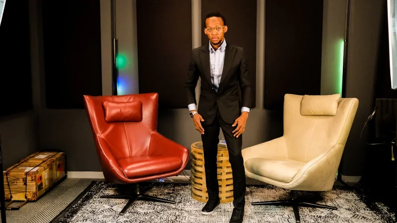 A black man in a black suit standing in a studio